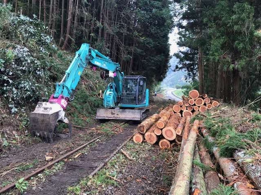 旧鉄道林で重機を使って伐採した木材を並べる森林再生作業